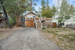 A two-story house with a garage, a staircase leading to the upper level, and a fenced yard. - Walk to Lake & Village | Hot Tub, Fire Pit, Fenced Yard & Lake Views (Big Bear Lake)