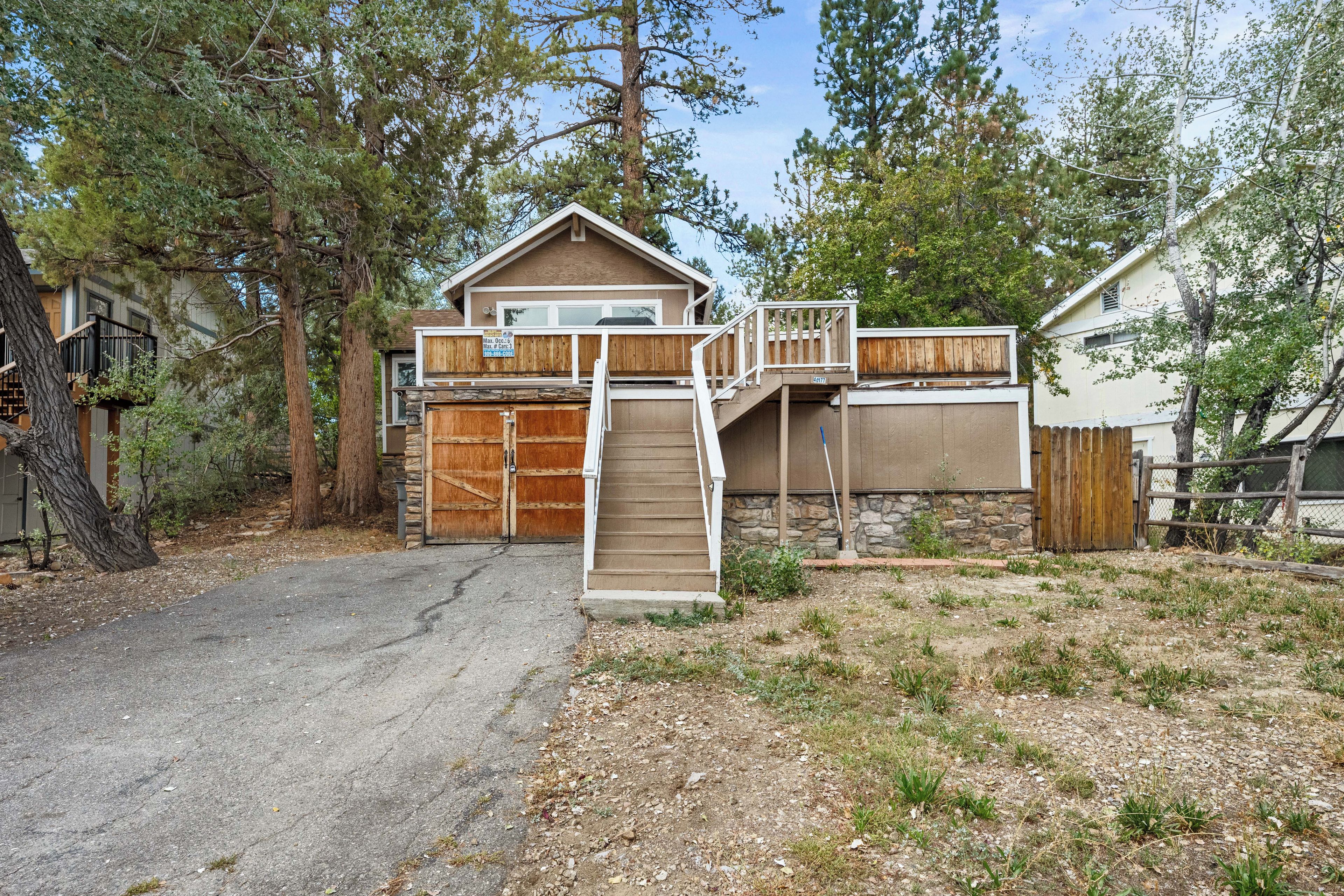 Une maison à deux étages avec une terrasse à l’avant, un garage et une allée menant à l’entrée.