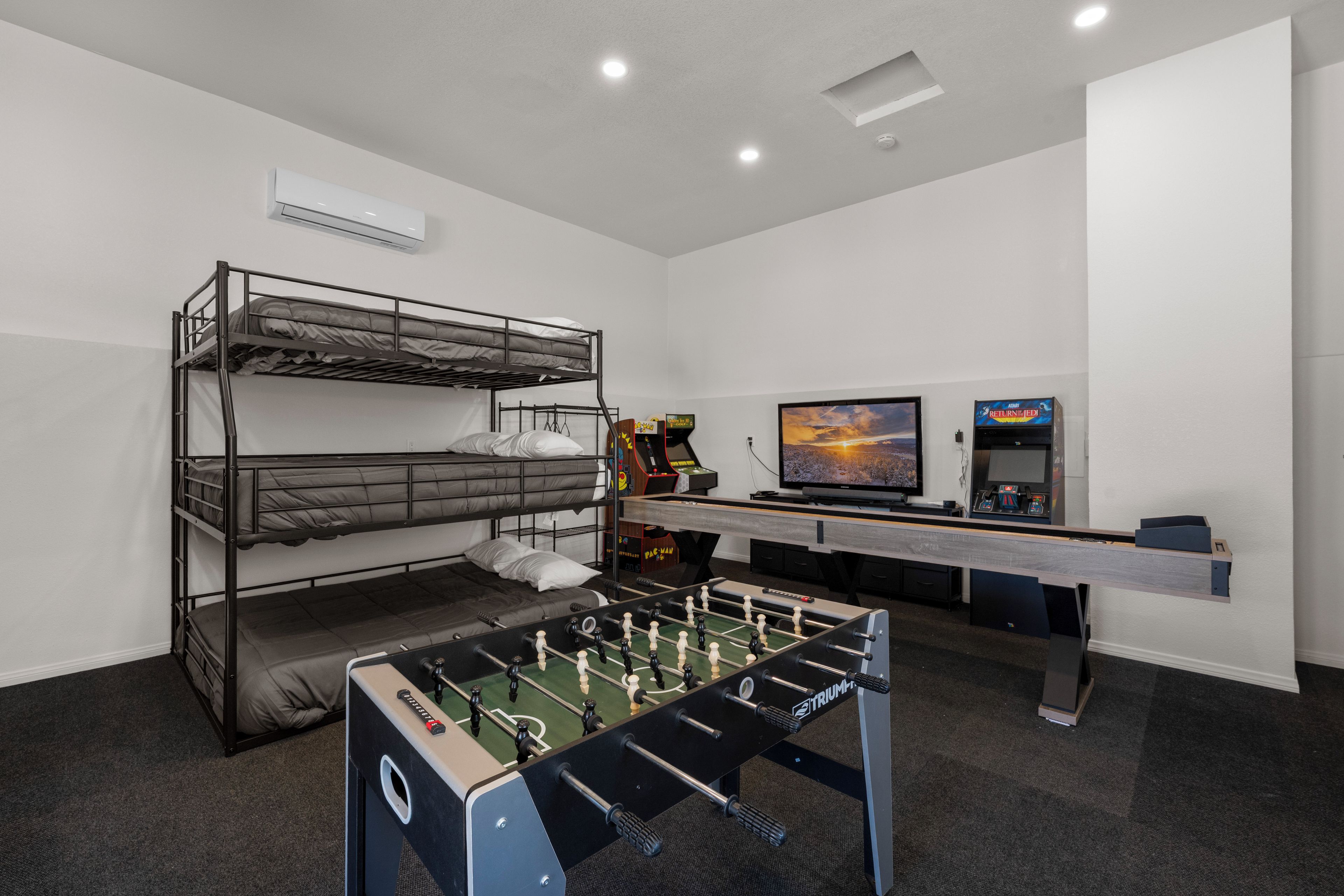 Ein Zimmer mit Stockbetten, einem Kicker, einem Fernseher und einer Spielkonsole.