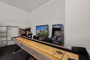 A room with a pool table, two arcade machines, and a television. - Big Bear Bunkhouse | Hot Tub, Game Room, A/C, EV Charging & Fenced Yard (Big Bear City)