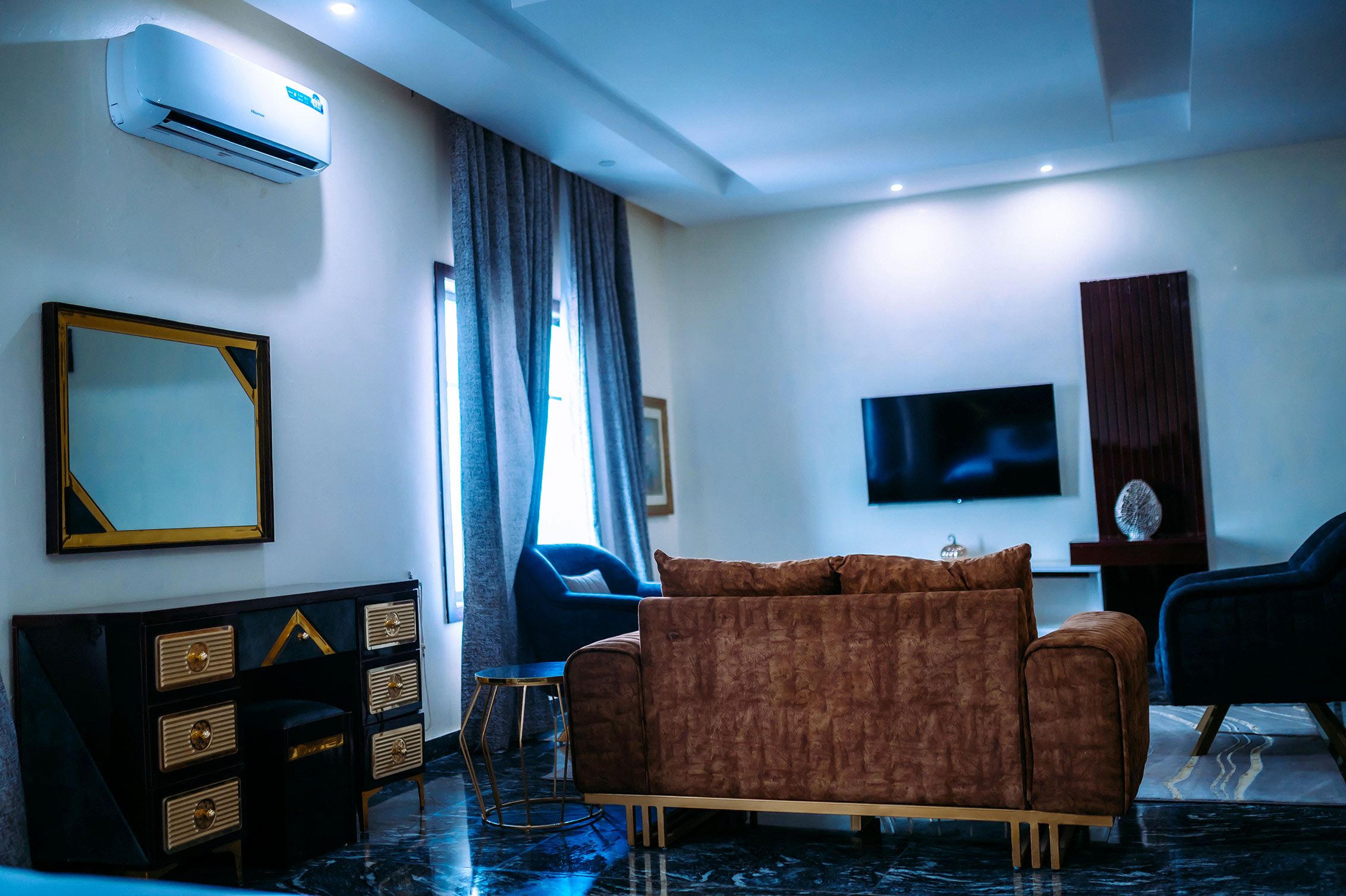 A modern living room with a sofa, a television, a mirror, and a dresser with drawers.