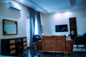 A modern living room with a sofa, a TV, a mirror, and a dresser. - Dejavu Hotel and Suite (Akure)