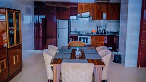 Ein Essbereich mit Holztisch und gepolsterten Stühlen, eine Küche mit Holzausstattung und einem eingebauten Kühlschrank.