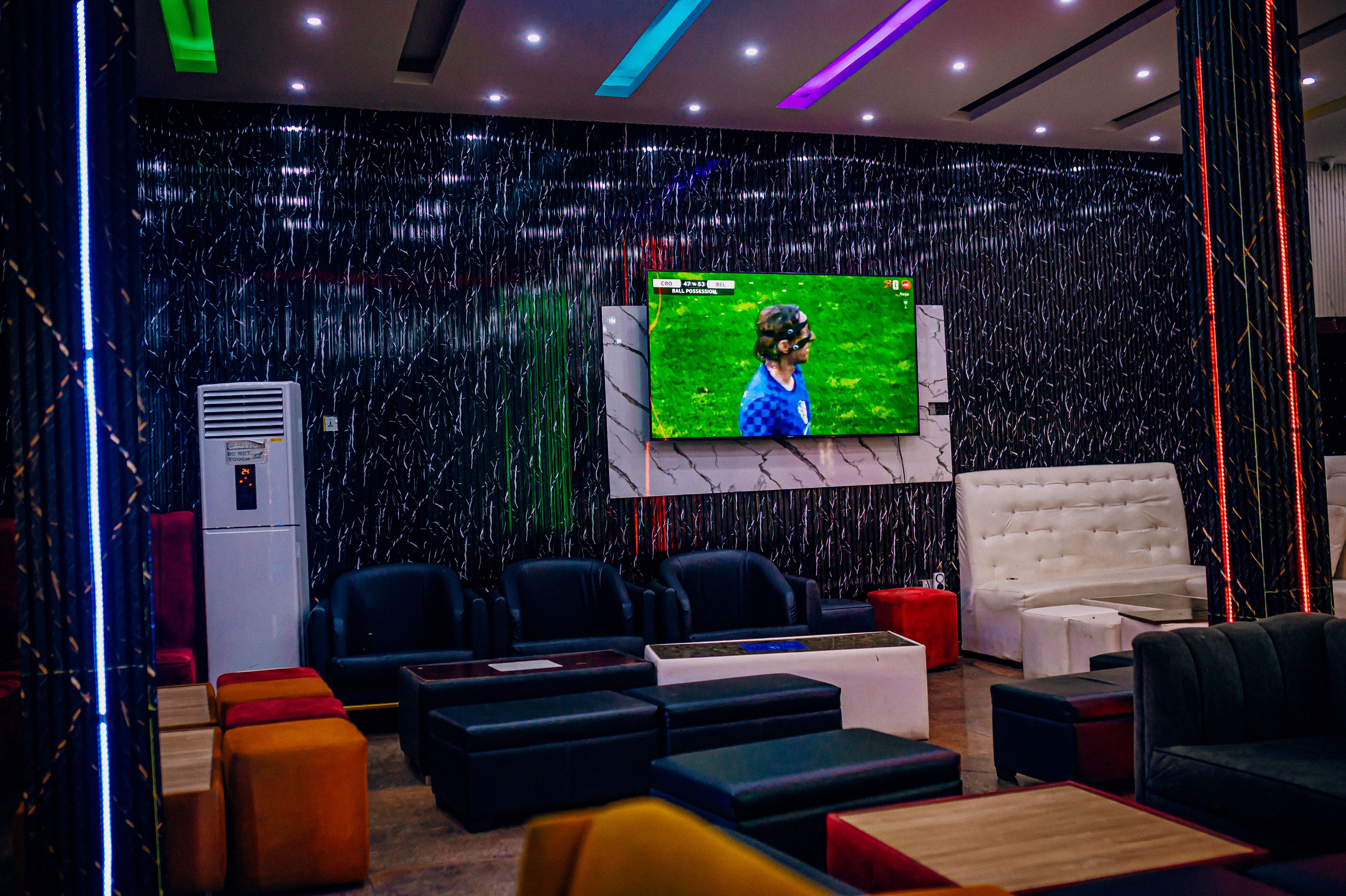 A modern living room with a flat-screen TV mounted on the wall, comfortable seating, and a decorative wall.