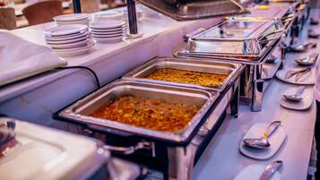A buffet setup with multiple serving trays and stacked plates.