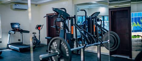 A gym with exercise equipment, a treadmill, and a mirror.
