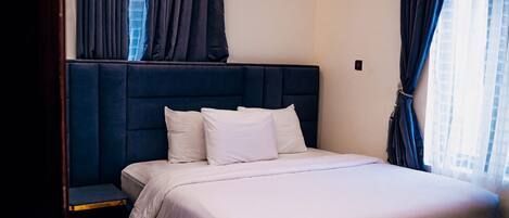 Una habitación de hotel con una cama grande, una mesita de noche y un equipo de aire acondicionado en la pared.