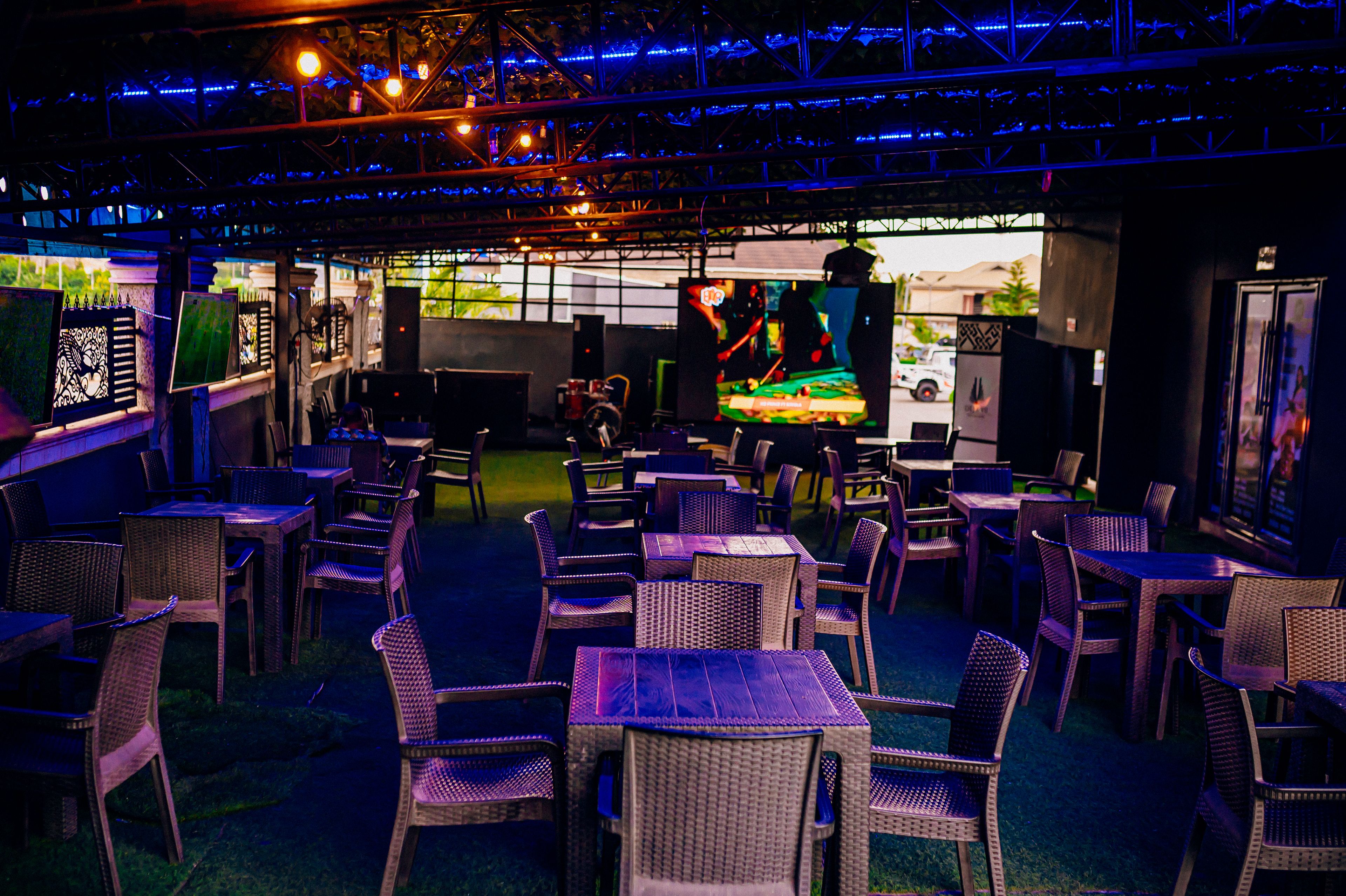 An indoor dining area with tables and chairs, a stage with a performer, and a view of the street outside.