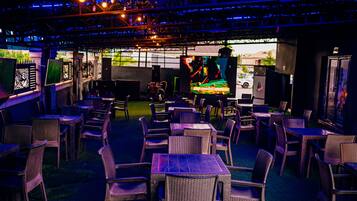 An indoor dining area with tables and chairs, a stage with a performer, and a view of the street outside.