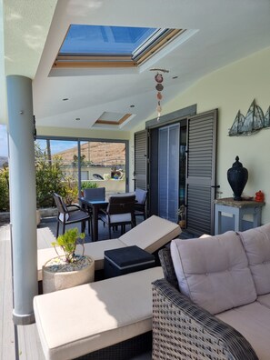 Une terrasse extérieure avec une table et des chaises, un canapé et un vase décoratif.