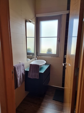 Une petite salle de bain avec un lavabo, un miroir et une fenêtre.