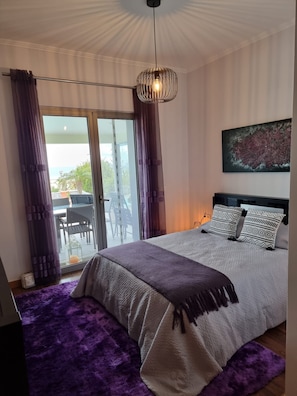 Une chambre à coucher avec un lit, une vue sur l’extérieur et un luminaire au plafond.