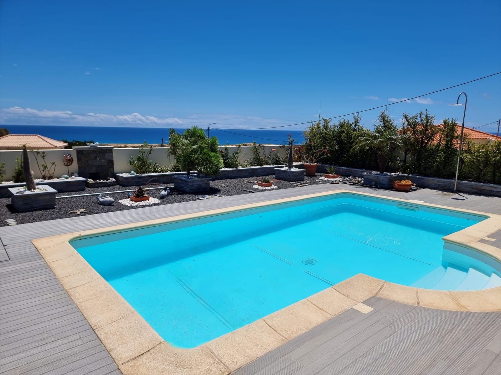 Une piscine rectangulaire à l’eau d’un bleu limpide, entourée d’une terrasse dont le bord est de couleur claire.