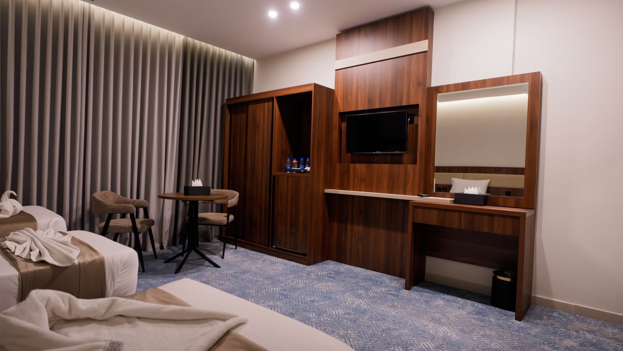 Una habitación de hotel con una cama, un escritorio, un televisor y un mini bar.