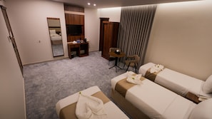 Habitación de hotel con dos camas, un escritorio, una silla, un televisor y un armario.