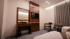 A hotel room with a bed, a desk with a TV, a small table with chairs, and a window with curtains. - فندق نسمات اليقين (Makkah)
