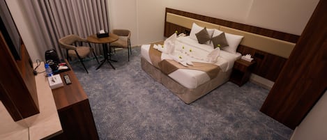 Una habitación de hotel con una cama, mesitas de noche, un escritorio y una silla.