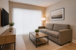 Ein modernes Wohnzimmer mit einer Couch, einem Couchtisch, einem Fernseher und einer Lampe.