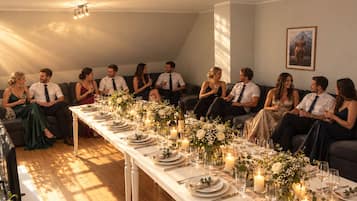 A room with a long dining table set for a meal, surrounded by sofas.