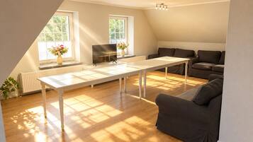 Ein modernes Wohnzimmer mit einem weißen Tisch, dunklen Sofas und einem Flachbildfernseher.