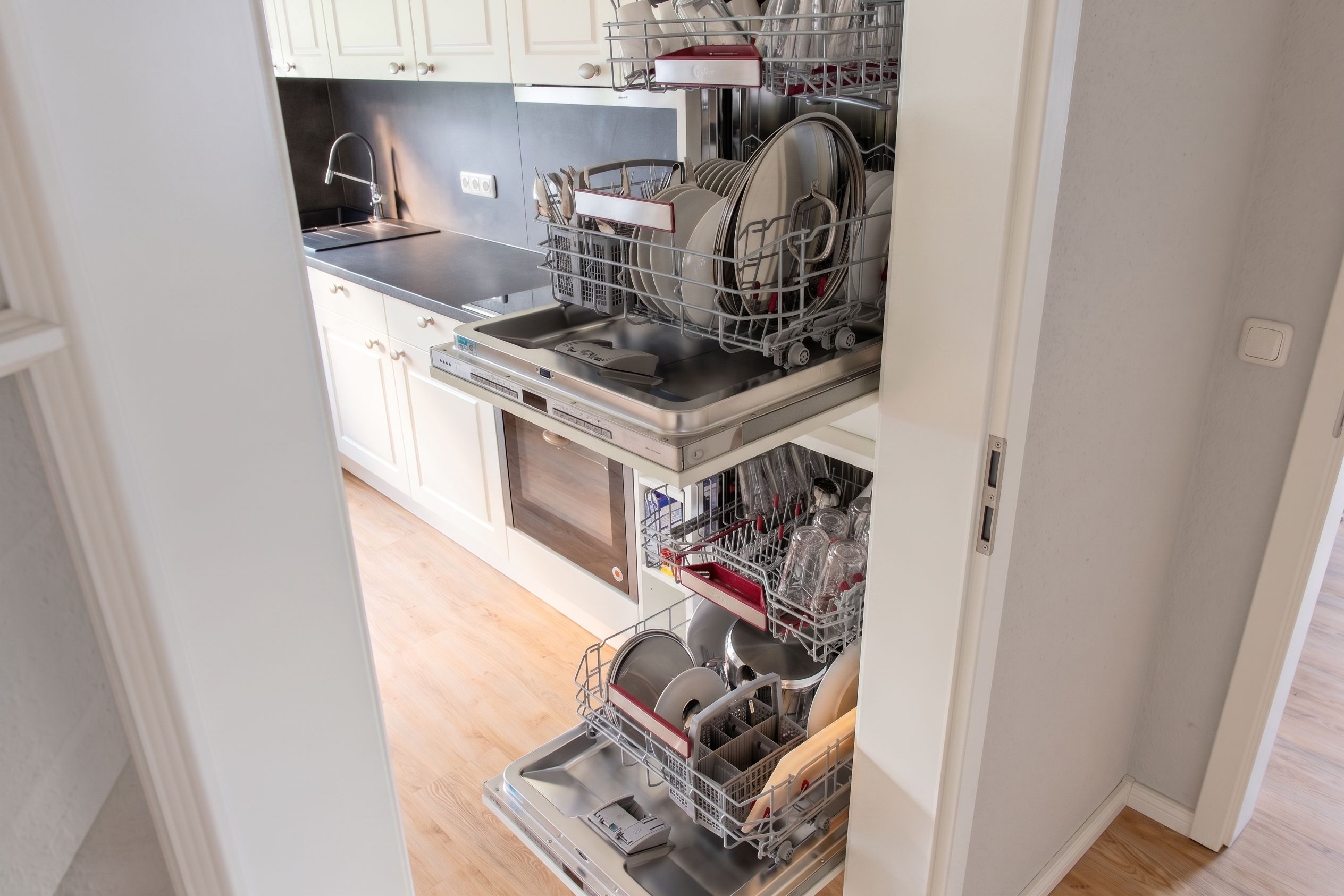 A kitchen with a dishwasher, sink, and cabinets.