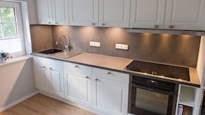 A modern kitchen with white cabinets, a stainless steel sink, and a built-in oven.