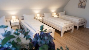 A room with three single beds, each with a bedside table and lamp, in a simple, clean design.