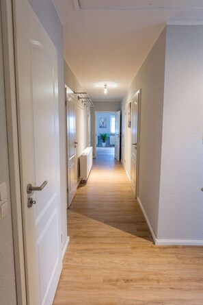 En hall med trägolv, vita väggar och dörrar som leder in till rummen.