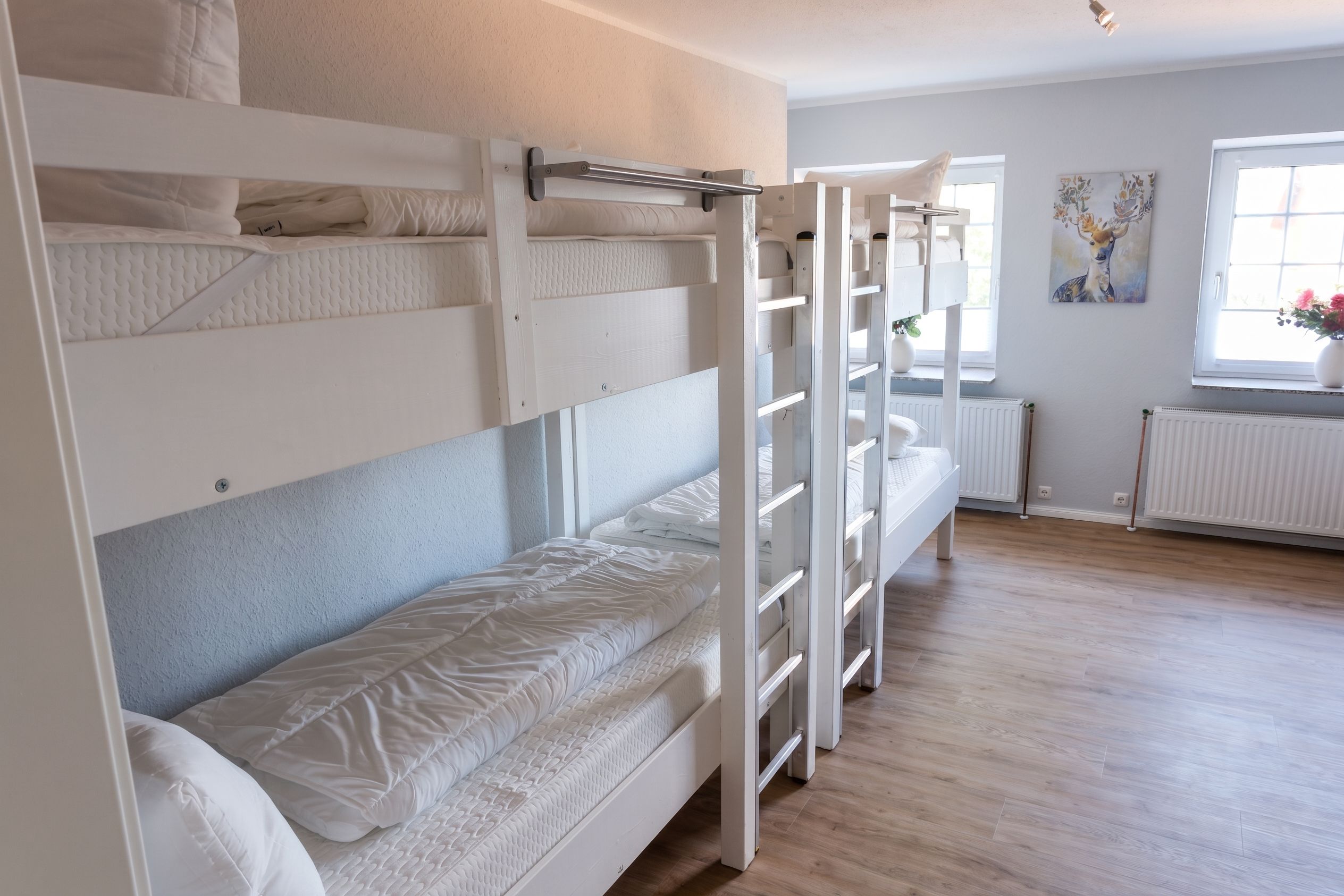 A bunk bed room with a window, radiator, and artwork on the wall.