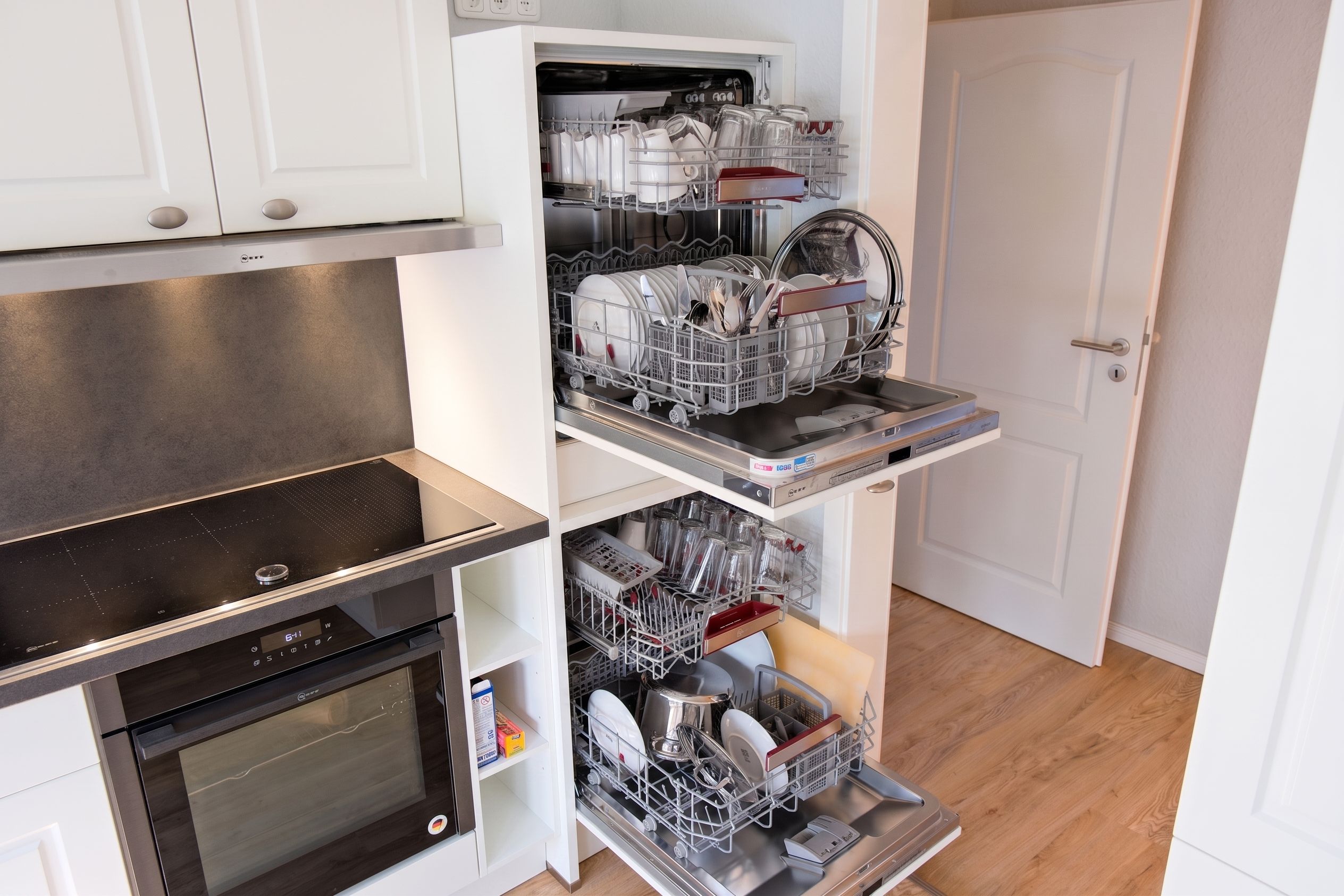 Eine kleine Küche mit integriertem Geschirrspüler, Backofen und einer Arbeitsplatte.