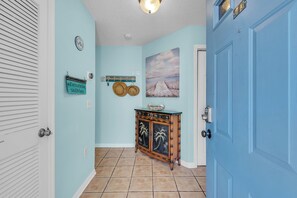 A hallway with light blue walls, a wooden cabinet with decorative items, and a door with a number plate. - On the Intracoastal | Pool | Fishing Pier | Walk to Beach | Indian Sands B3 (Indian Shores)