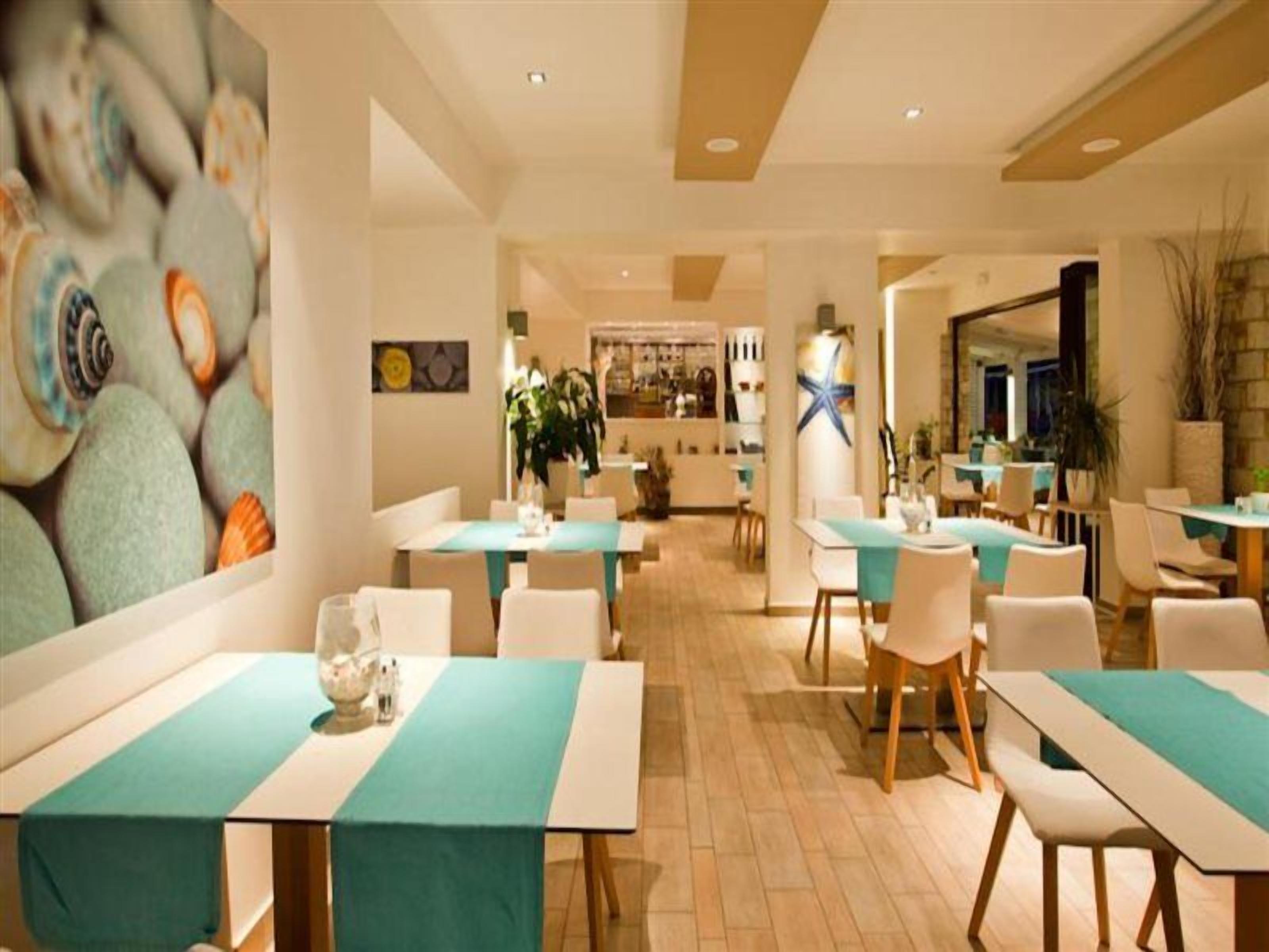 Un ristorante con diversi tavoli e sedie, un'isola centrale e una parete con motivo decorativo.