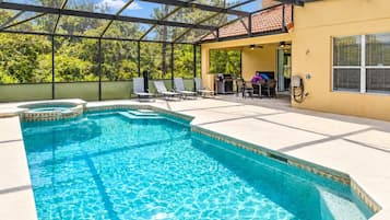 Piscina com estrutura de toldo, espreguiçadeiras e área de terraço com mesa e cadeiras.
