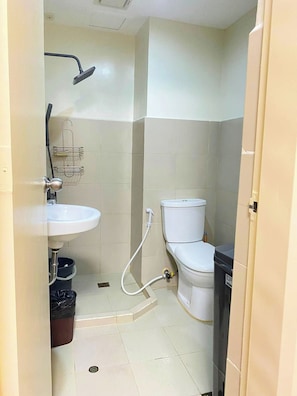 A small bathroom with a toilet, a sink, and a shower.