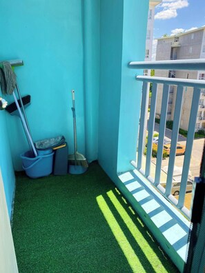 A balcony with artificial grass, a mop, a broom, and a dustpan.