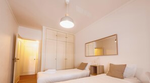 Een slaapkamer met twee bedden, een kledingkast, een spiegel en een nachtkastje.