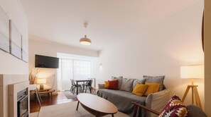 A modern living room with a sofa, a dining table, and a TV. - Mareantes Atlantic House - comfortable 2-bedroom apartment in Cascais (Cascais)