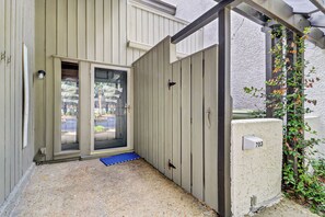 A gated entrance with a blue mat, a metal gate, and a concrete wall with a number plate. - Sunset Rentals | Tennismaster 703 | Dog Friendly (Hilton Head Island)