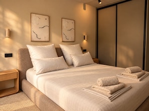 Une chambre moderne avec un grand lit, deux appliques murales et un placard à portes coulissantes.