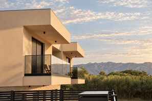 Un bâtiment moderne doté d’un balcon, offrant une vue sur les montagnes et s’ouvrant sur un ciel dégagé.