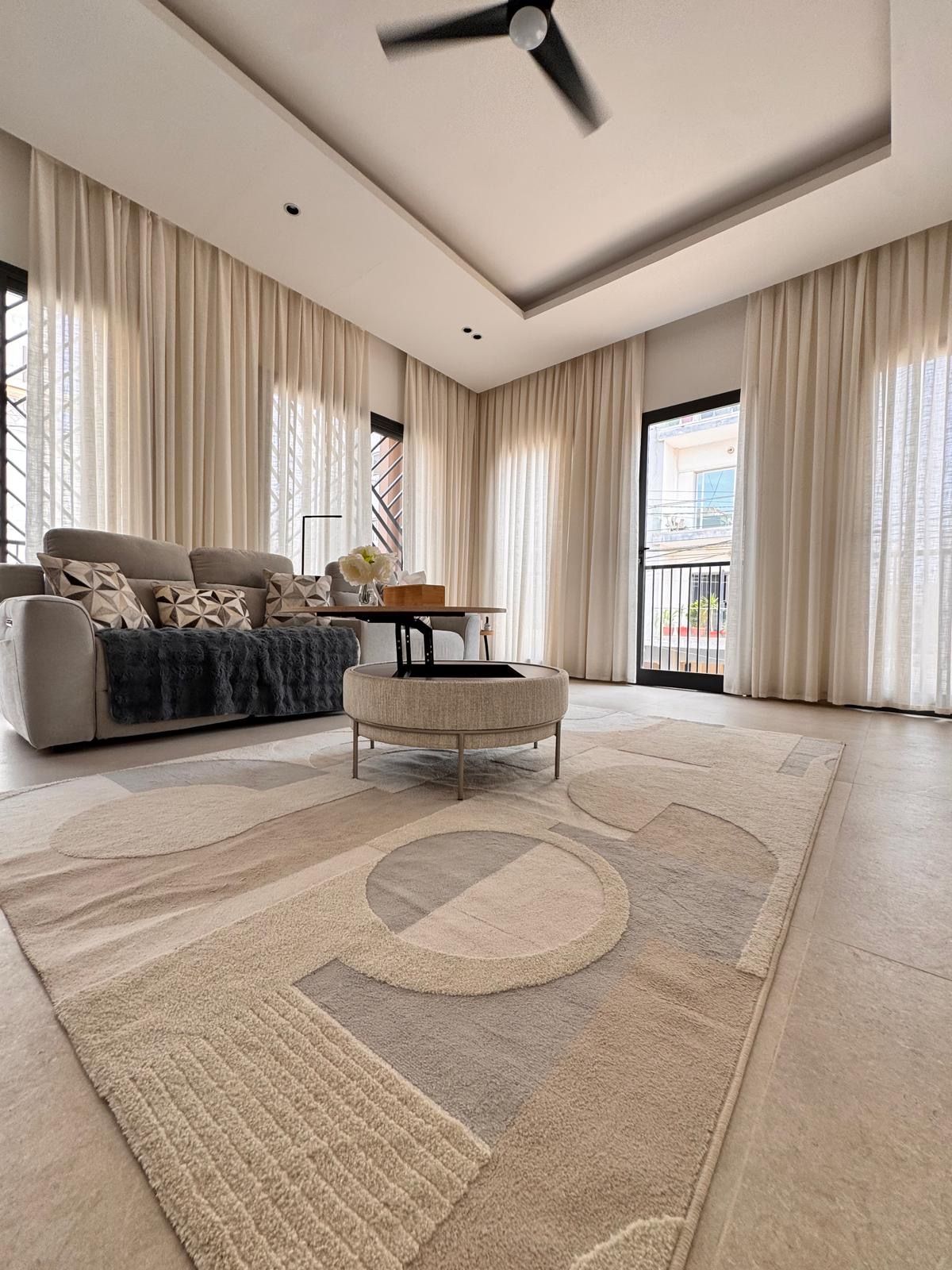 A spacious living room with a sofa, ottoman, and a ceiling fan.