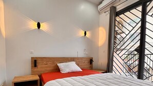 Quarto com cama, mesa de cabeceira e luminárias fixadas na parede.