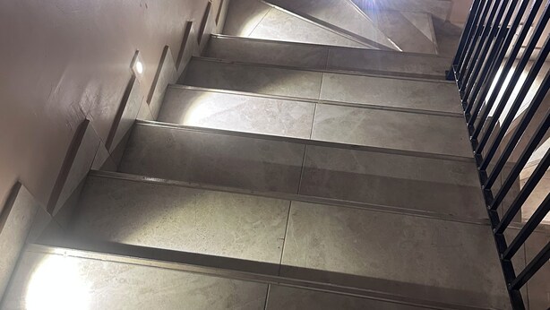 Uma escada com corrimão e iluminação no topo.