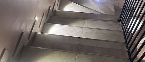 A staircase with a handrail and a light source at the top.