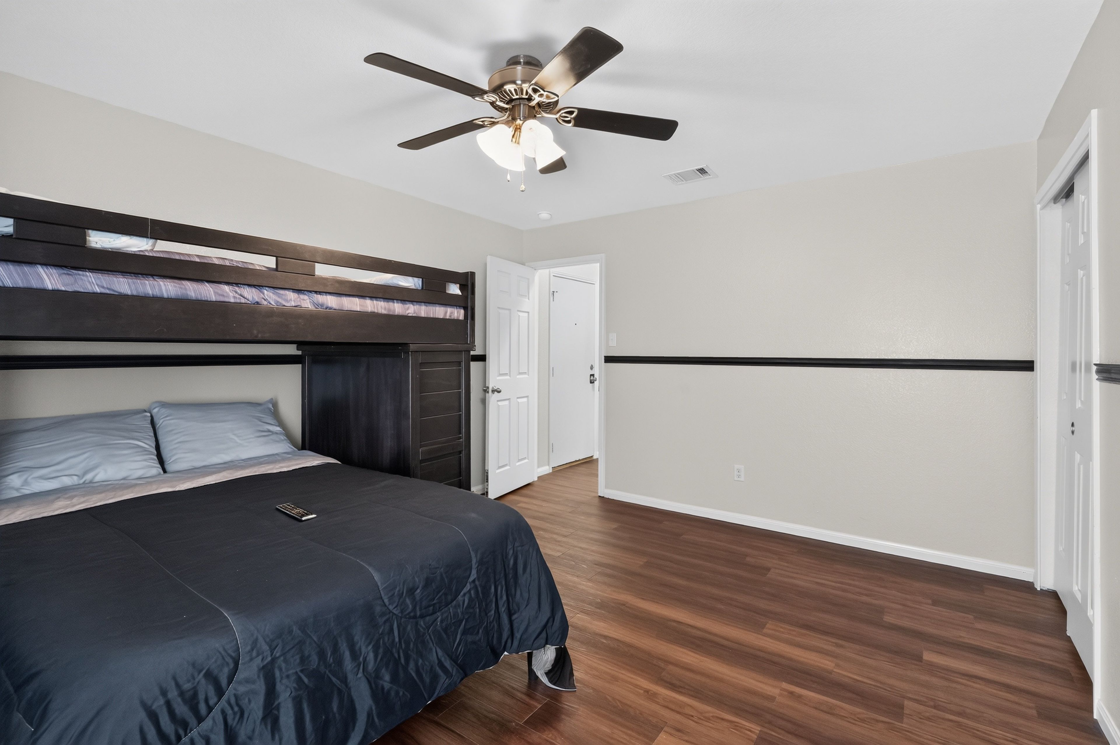 A bedroom with a bunk bed, a ceiling fan, and a door.