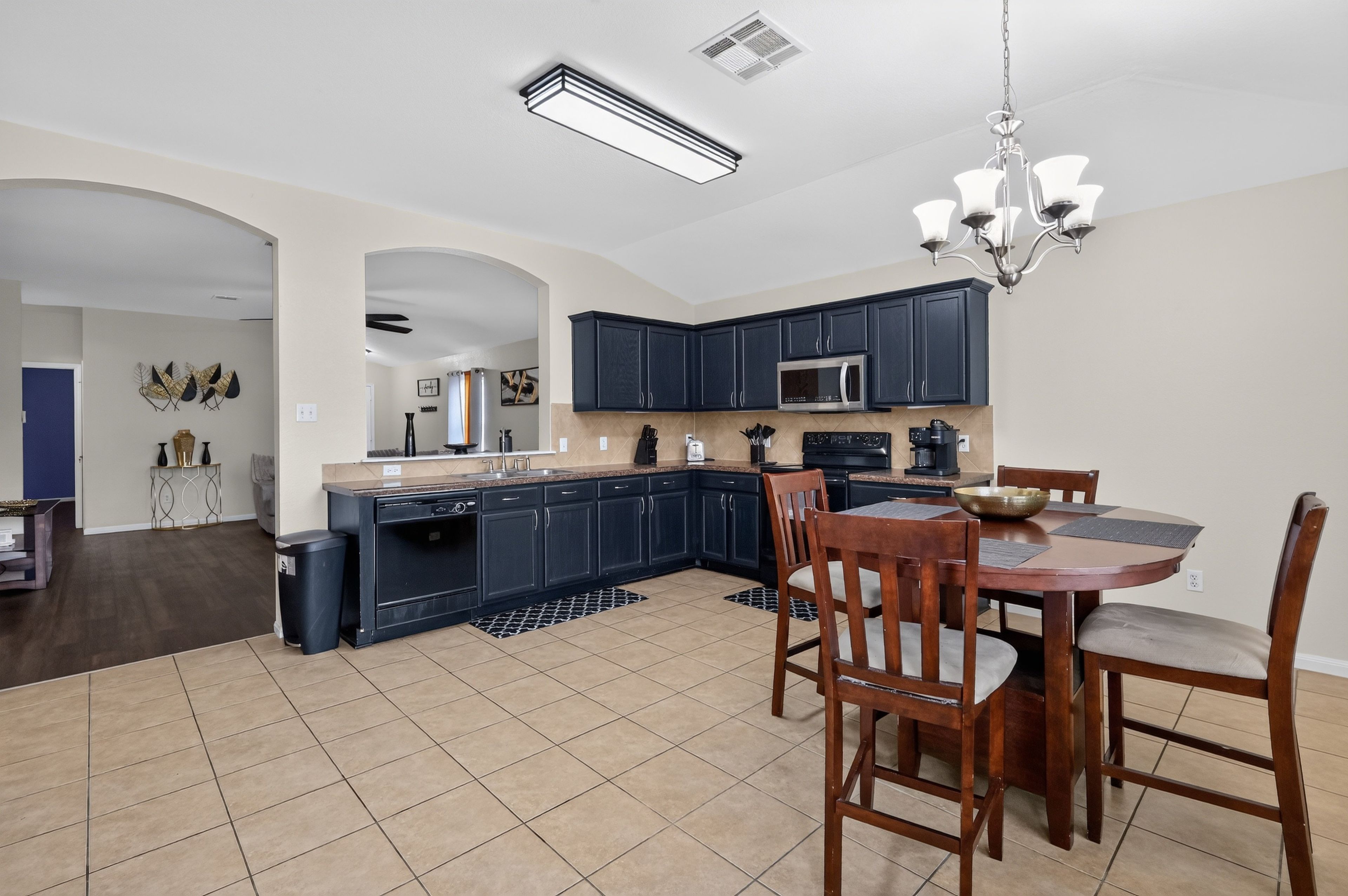A modern kitchen with dark cabinets, a microwave, and a dining area with a table and chairs.