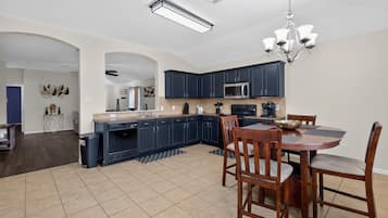 A modern kitchen with dark cabinets, a microwave, and a dining area with a table and chairs.