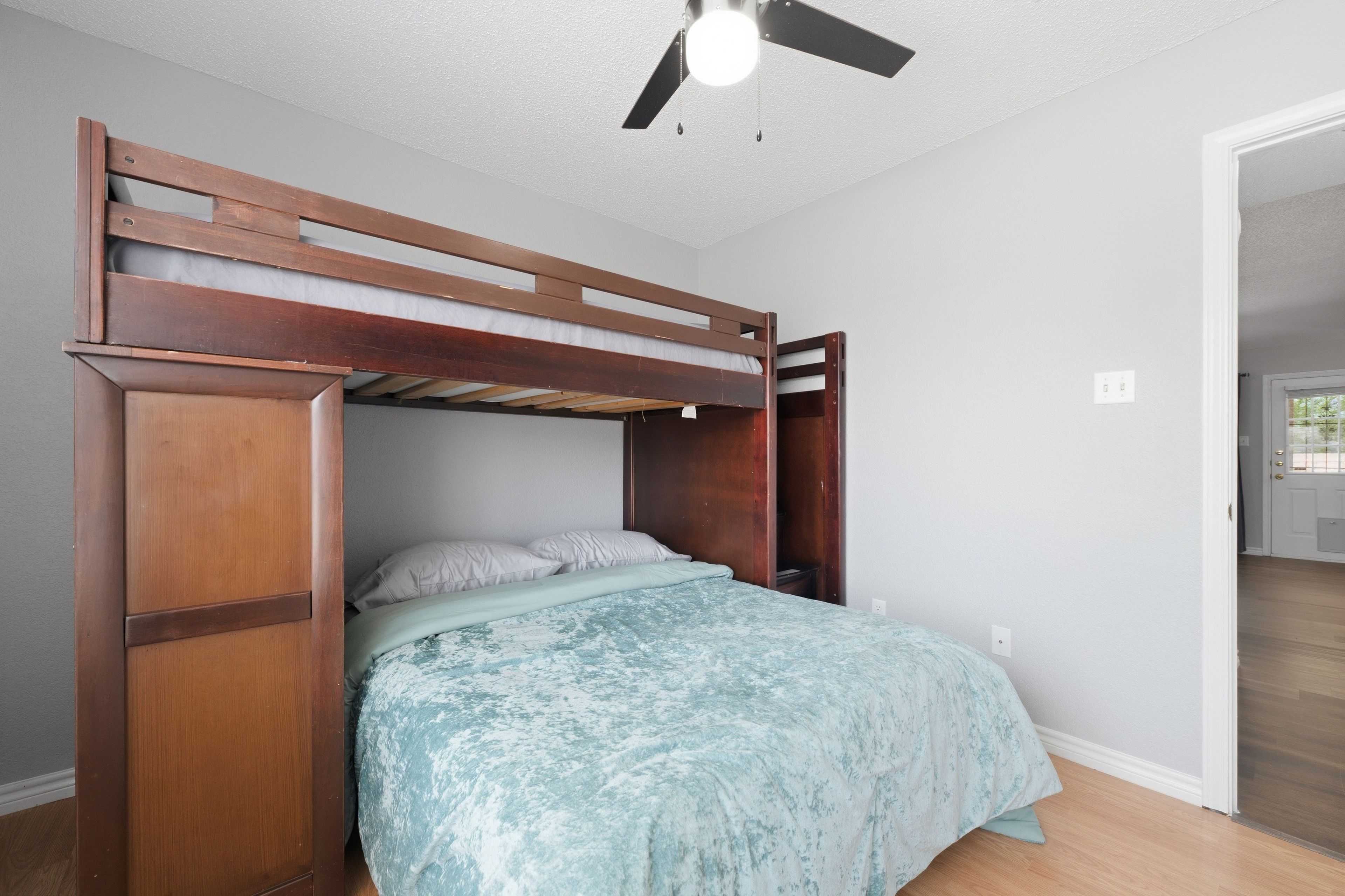 Ein Etagenbett mit Holzrahmen, Deckenventilator und einer Leuchte.
