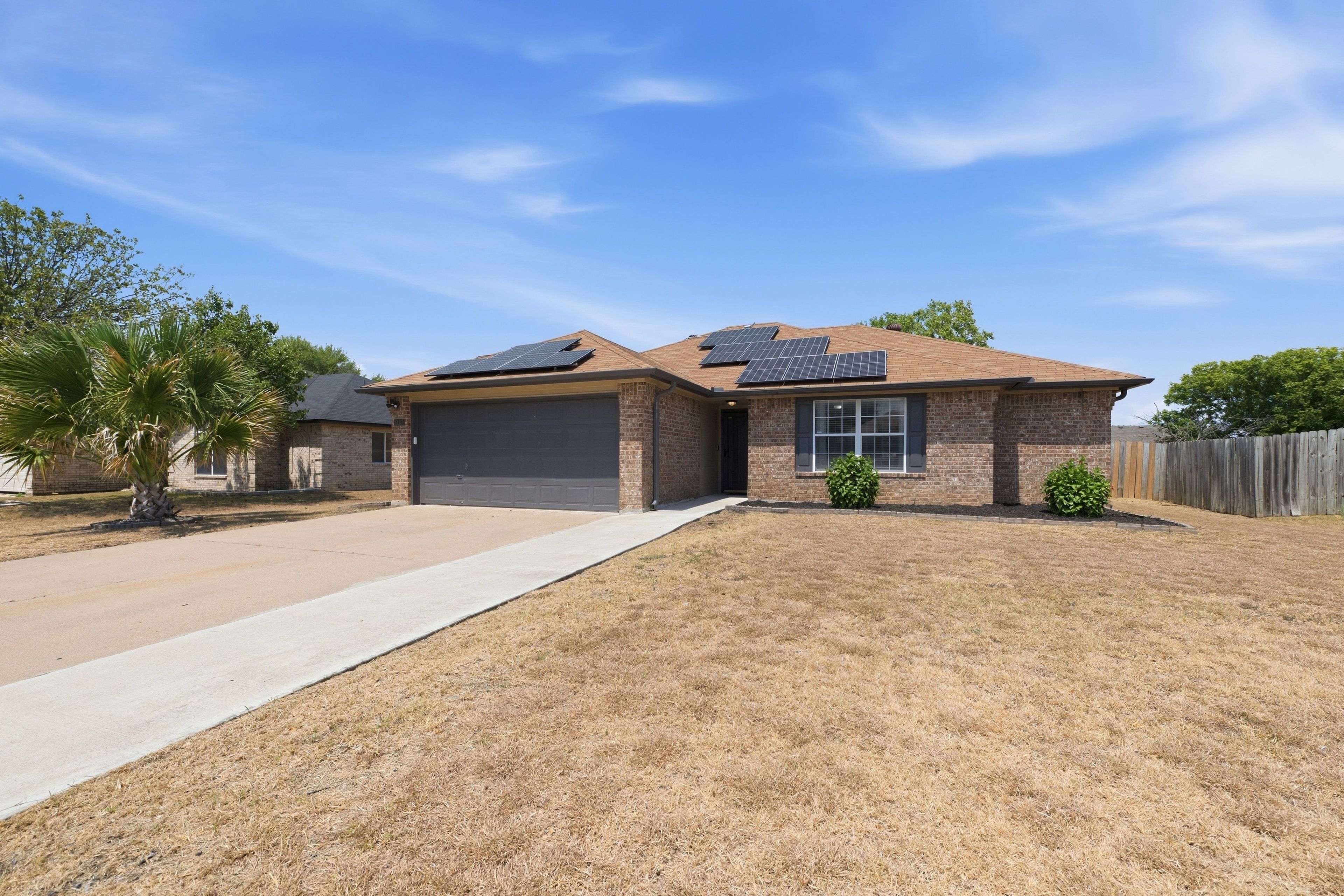 A residential house with a brick exterior, a garage, and solar panels on the roof.