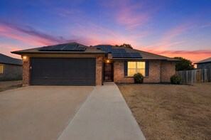 A residential house with a garage, solar panels, and a driveway. - New! Cozy 3BR Retreat Near Fort Hood Killeen (Killeen)